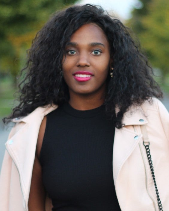 The author, Alexis, smiling for the camera in a black top and a baby pink motorcycle jacket