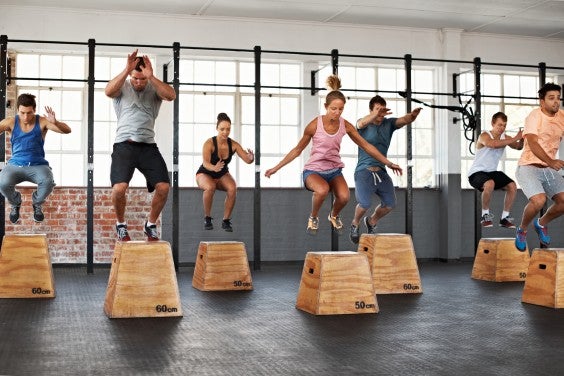 Men and women box jumping in a fitness class