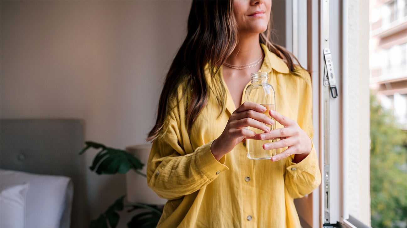 woman drinking water by a window