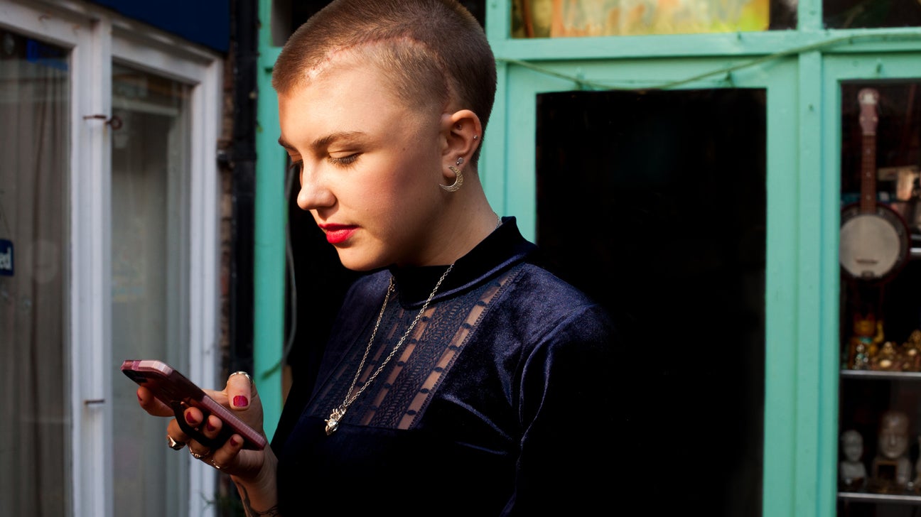 Person with short hair and red lipstick looks at phone.