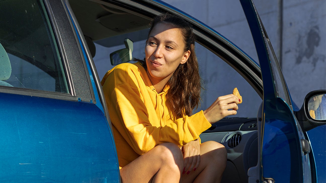 Young woman eating in a car