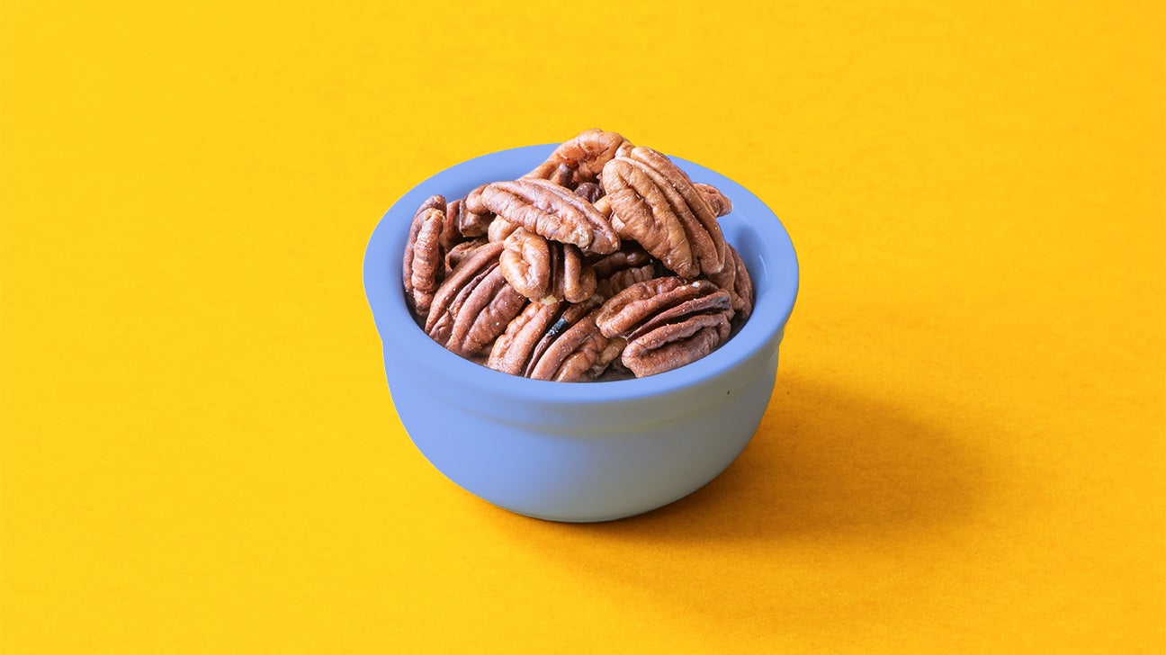 pecan nuts in a bowl on yellow background header