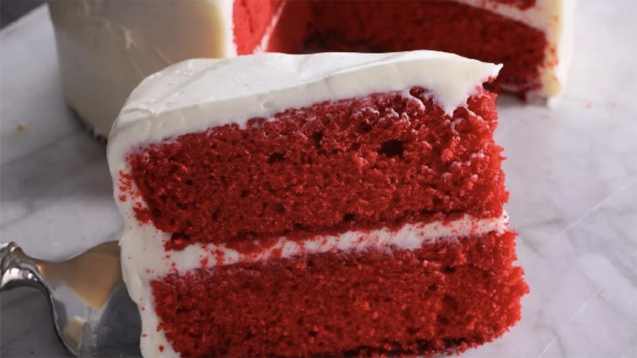 Slice of red velvet cake with white frosting