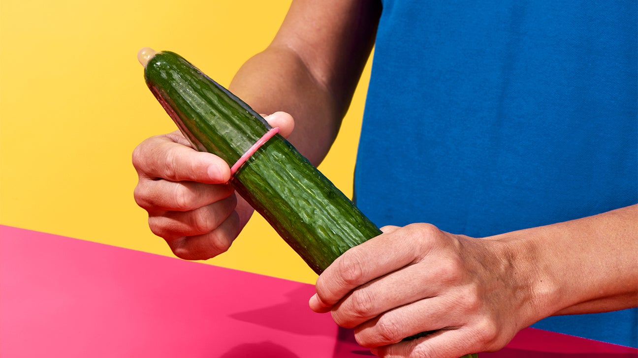 putting pink condom on cucumber