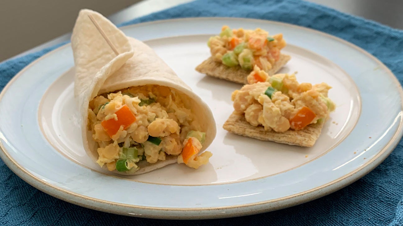 Chickpea salad in a wrap and on crackers on a blue-ringed plate.