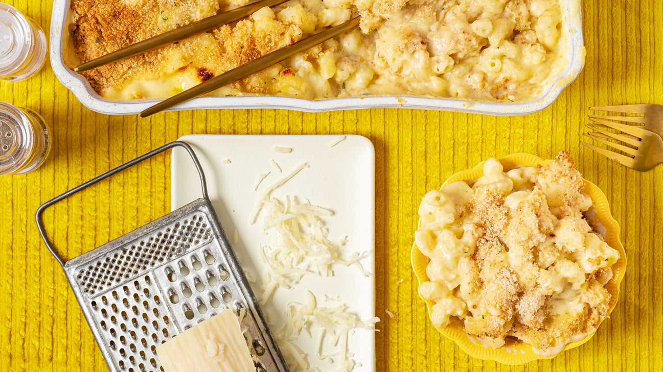 shredded cheese next to dish full of macaroni and cheese