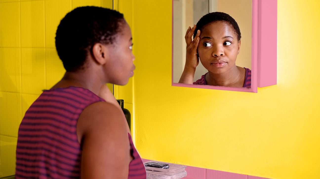 female looking in the mirror at postpartum acne