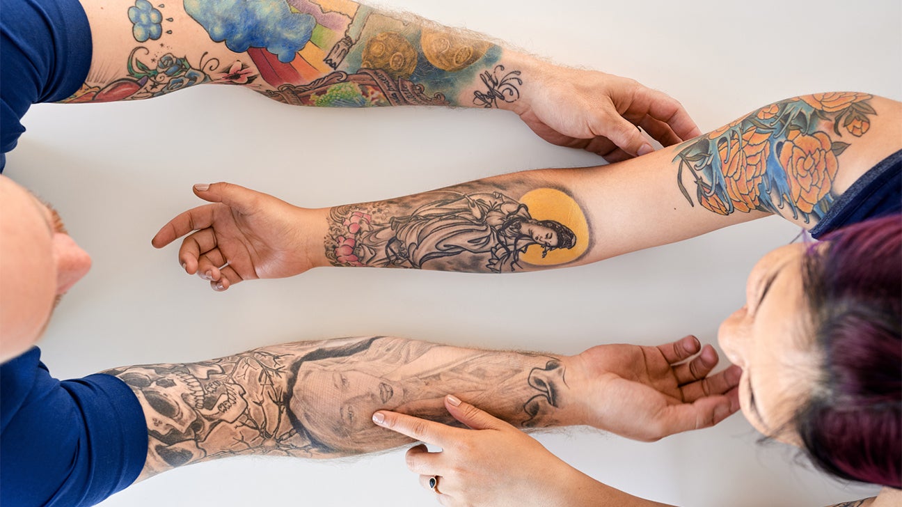 two people examining each other's tattoos on their arms