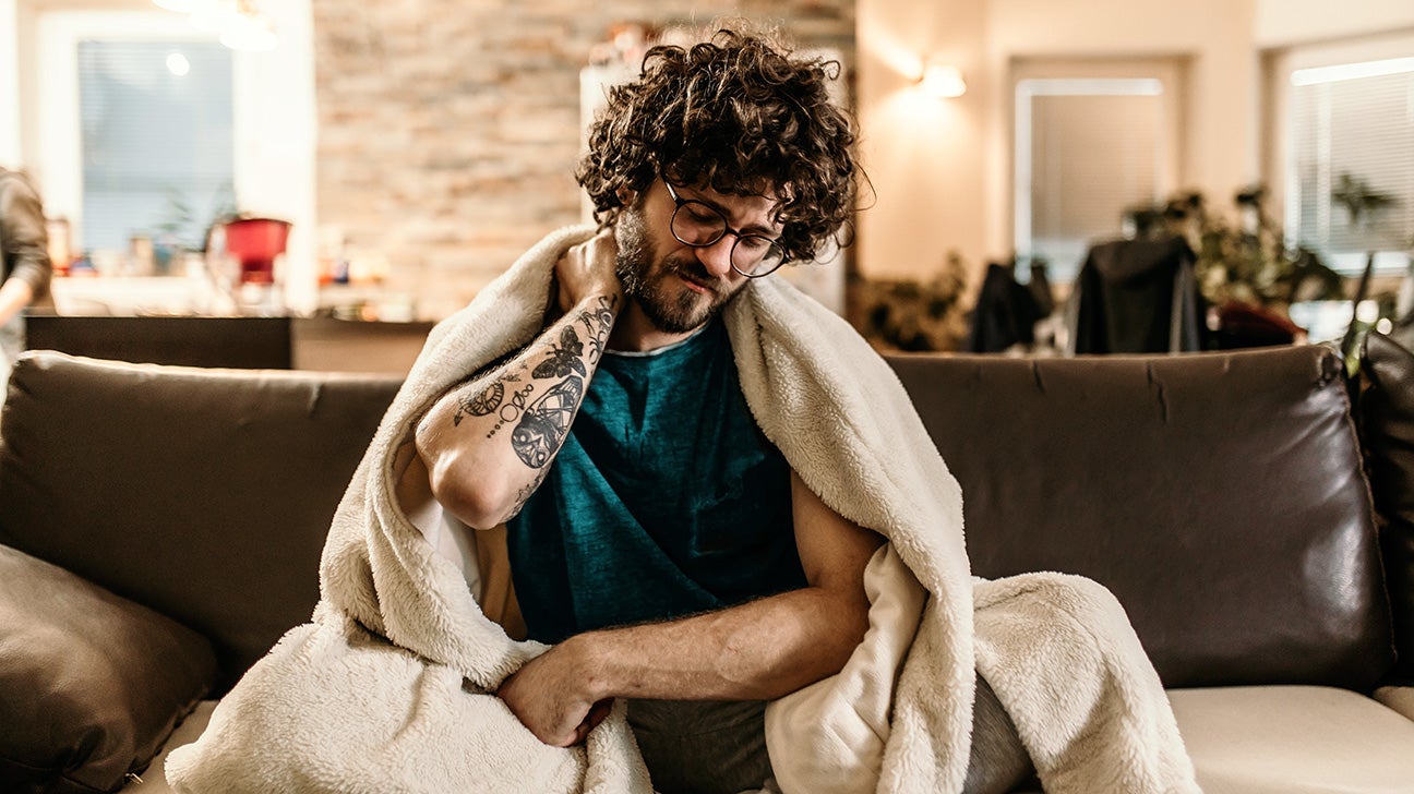 man with tattoo sitting on couch with aches